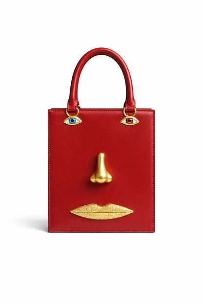 Red handbag with gold accents shaped like a face on a white background