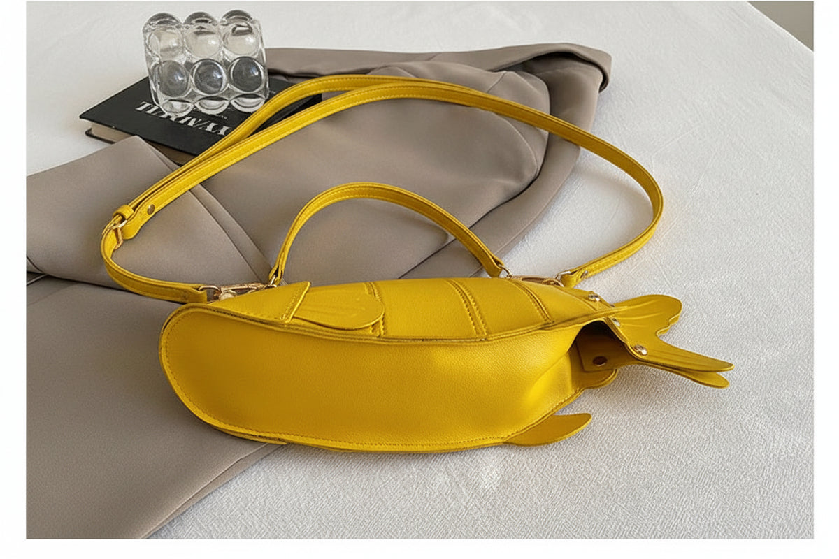 A bright yellow handbag with a whale tail design on the end, shown on a light gray fabric surface with a gray garment and glass cups in the background. A dark gray banner at the bottom has Chinese text and 'THE DETAILS SHOW'.