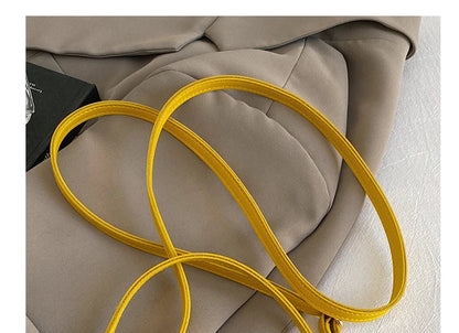 Close-up detail shot of a yellow handbag strap draped over taupe fabric, with gold-tone hardware and Chinese text overlay reading '可调肩带' and 'THE DETAILS SHOW'.