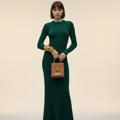 Person holding a unique handbag with face design elements against a neutral background