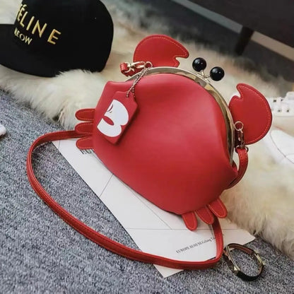 Red crab-shaped handbag on a textured surface with a blurred background