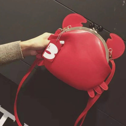 Red heart-shaped bag with a strap held by a hand against a dark background