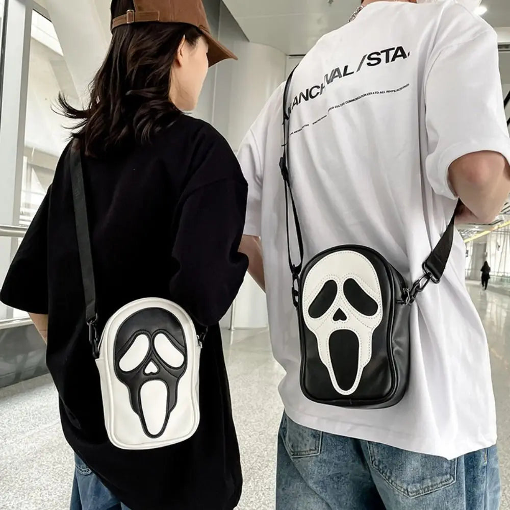 Two people wearing crossbody bags with scream face designs in a modern indoor setting.