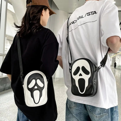 Two people wearing crossbody bags with scream face designs in a modern indoor setting.