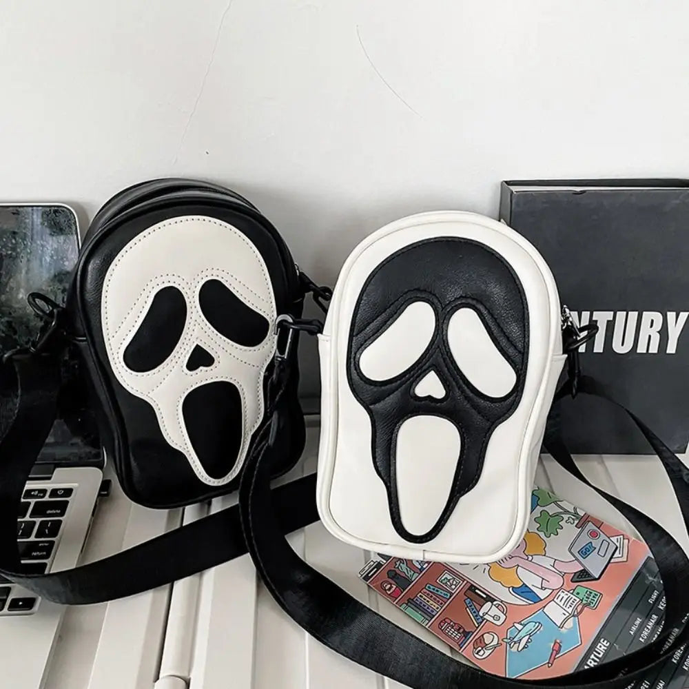 Black and white mask-shaped pouches on a desk with a laptop and books in the background