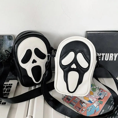 Black and white mask-shaped pouches on a desk with a laptop and books in the background